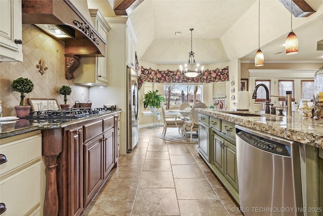 kitchen featuring appliances with stainless steel finishes, decorative backsplash, hanging light fixtures, dark stone counters, and cream cabinets