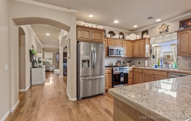 kitchen with decorative backsplash, ornamental molding, stainless steel appliances, and light wood-type flooring