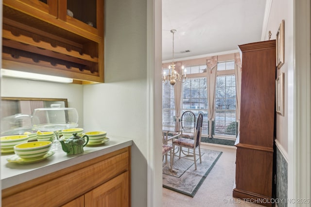 kitchen featuring an inviting chandelier, hanging light fixtures, light carpet, and ornamental molding