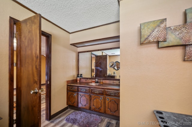 bathroom featuring vanity, crown molding, hardwood / wood-style floors, and a textured ceiling