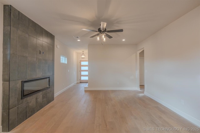 unfurnished living room featuring ceiling fan, light wood-type flooring, and a fireplace