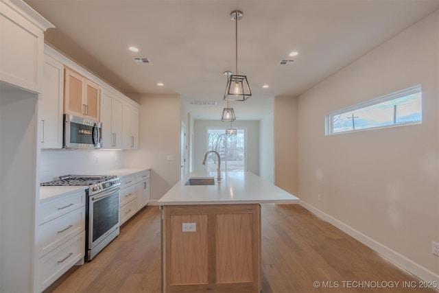 kitchen with sink, an island with sink, white cabinets, and appliances with stainless steel finishes