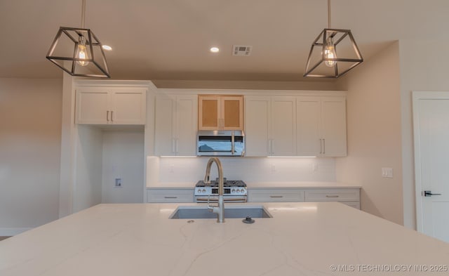 kitchen with white cabinetry, hanging light fixtures, and appliances with stainless steel finishes