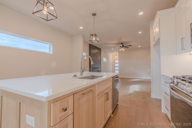 kitchen featuring sink, decorative light fixtures, stainless steel appliances, and an island with sink