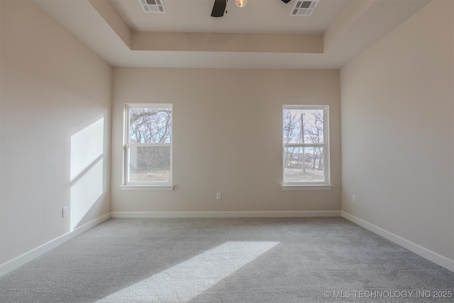 unfurnished room with light carpet, ceiling fan, and a tray ceiling