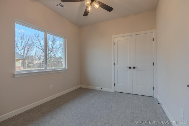 unfurnished bedroom featuring ceiling fan, a closet, and light carpet