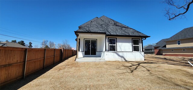 back of property featuring fence, roof with shingles, and brick siding