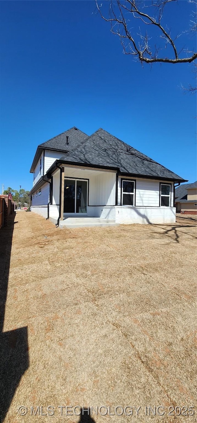 rear view of property featuring a shingled roof