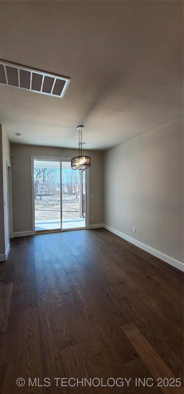 empty room with dark wood-type flooring, baseboards, and a chandelier