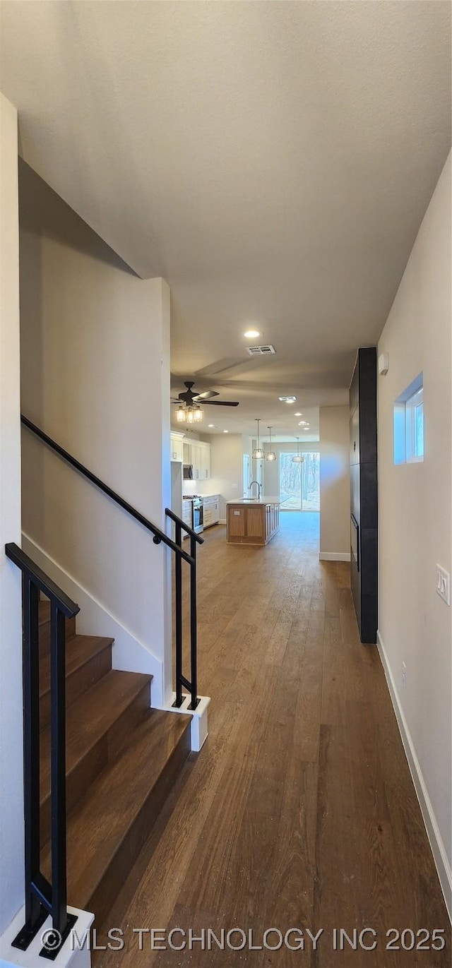 staircase featuring visible vents, baseboards, wood finished floors, and a ceiling fan