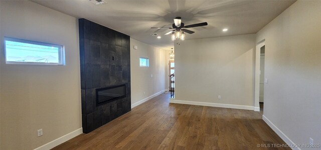 empty room with plenty of natural light, a fireplace, ceiling fan, dark wood finished floors, and recessed lighting