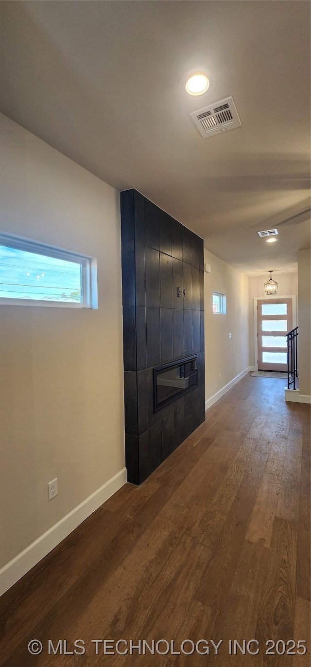 hallway with dark wood-type flooring, baseboards, and visible vents