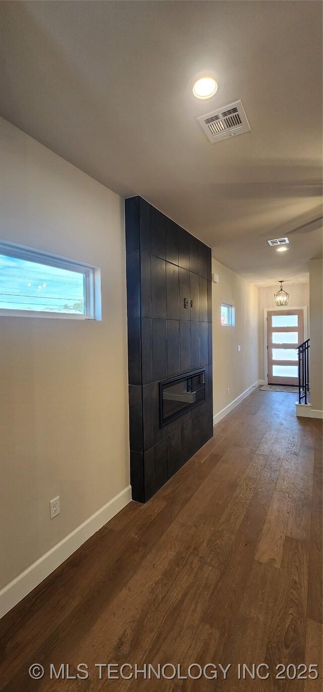 unfurnished living room with a tile fireplace, dark wood finished floors, and baseboards