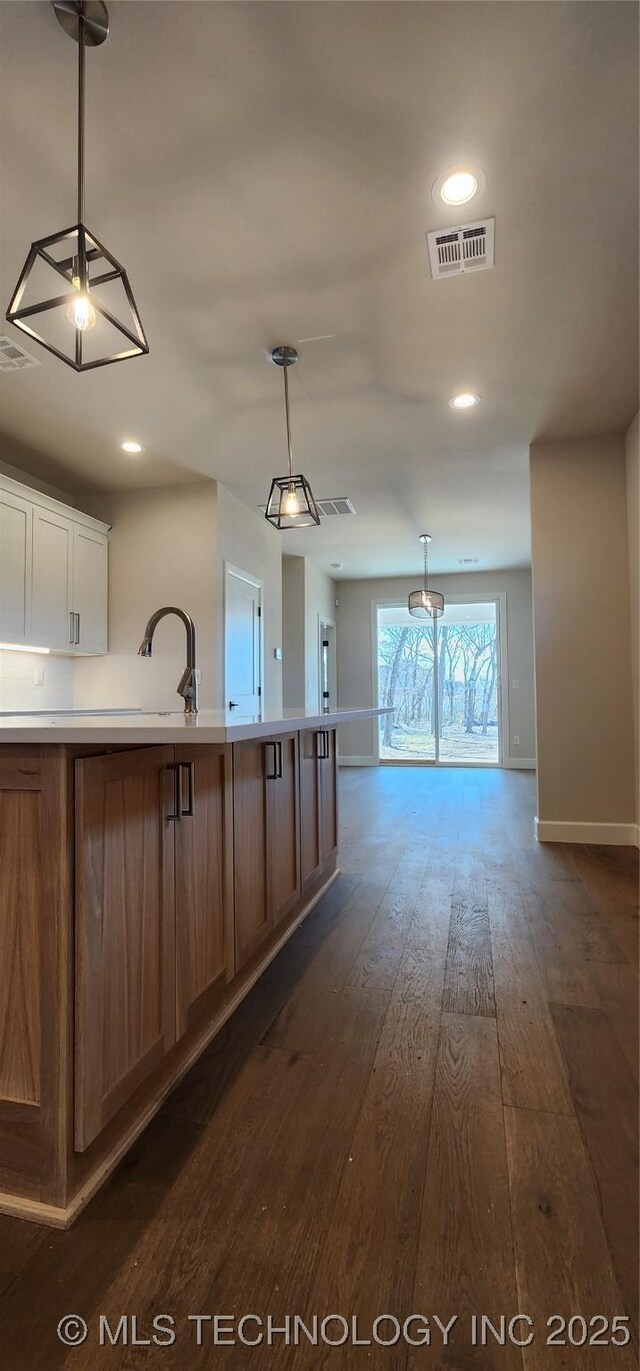 kitchen with light countertops, dark wood-type flooring, baseboards, open floor plan, and hanging light fixtures