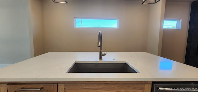kitchen featuring a sink, stainless steel dishwasher, healthy amount of natural light, and light stone counters