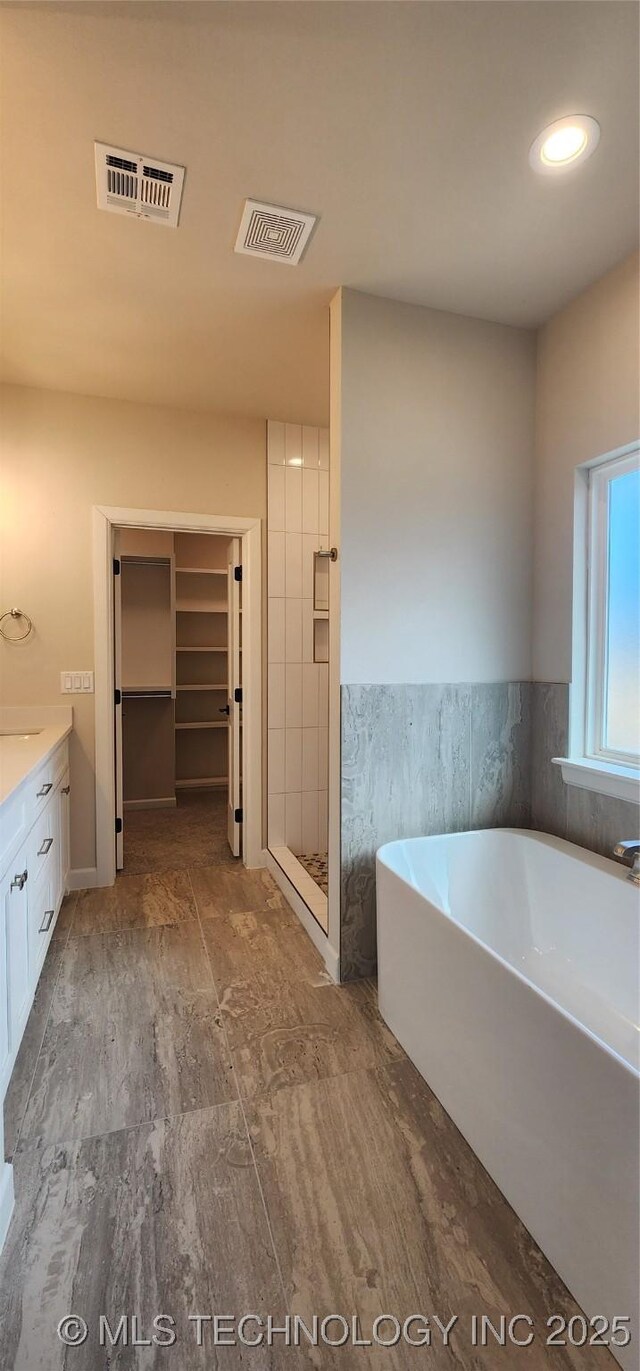 bathroom featuring vanity, a freestanding tub, a shower stall, and recessed lighting