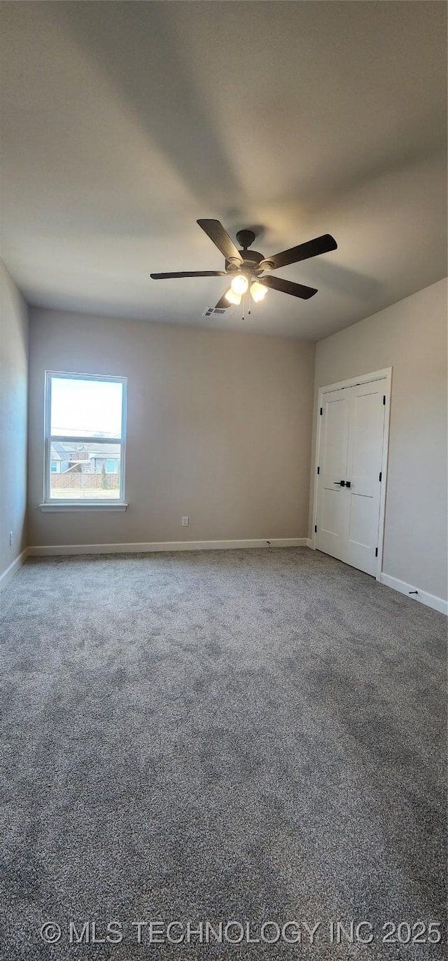 carpeted spare room featuring visible vents, baseboards, and a ceiling fan