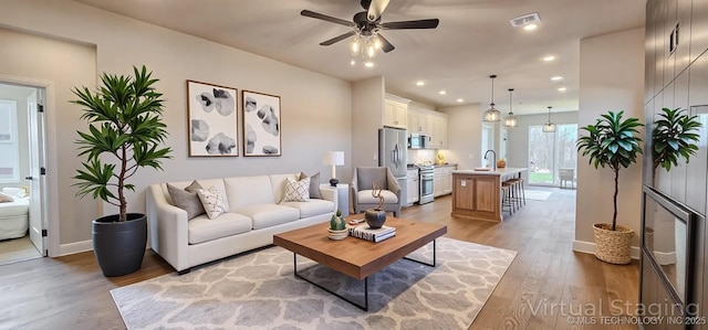 living room with a ceiling fan, wood finished floors, baseboards, and recessed lighting
