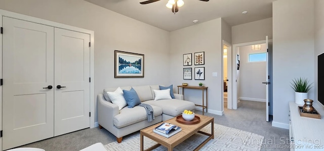 living area with light carpet, ceiling fan, and baseboards