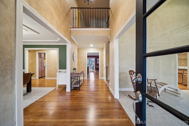 foyer entrance with hardwood / wood-style flooring, ornamental molding, and a high ceiling