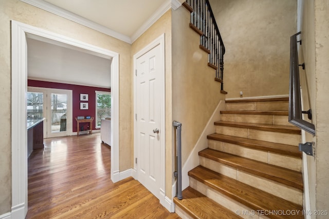 staircase with hardwood / wood-style flooring and ornamental molding