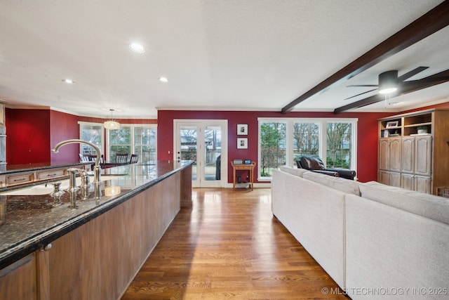 living room featuring beamed ceiling, ceiling fan, and wood-type flooring