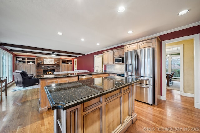 kitchen with crown molding, a brick fireplace, kitchen peninsula, a kitchen island, and stainless steel appliances