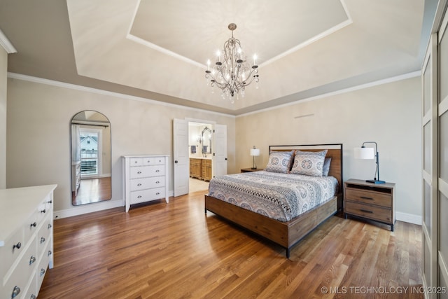 bedroom with an inviting chandelier, hardwood / wood-style floors, crown molding, and a raised ceiling