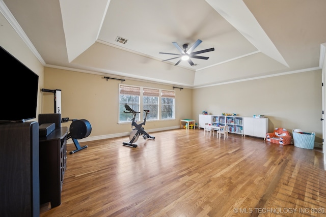 exercise room with crown molding, ceiling fan, a tray ceiling, and hardwood / wood-style floors