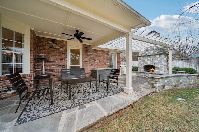view of patio / terrace with an outdoor stone fireplace, a ceiling fan, fence, and a pergola