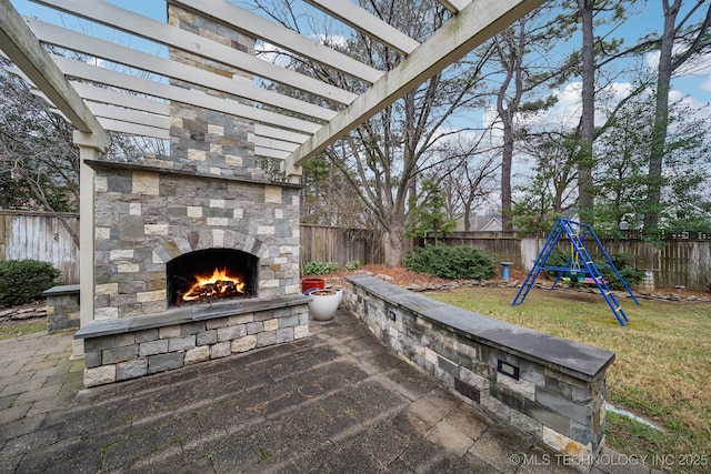 view of patio featuring a playground and an outdoor stone fireplace