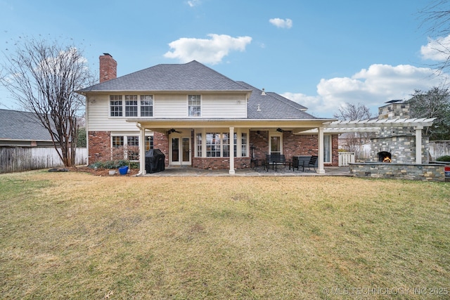 rear view of house with an outdoor stone fireplace, ceiling fan, a yard, a pergola, and a patio