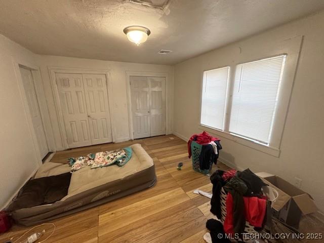 bedroom with two closets and light wood-type flooring