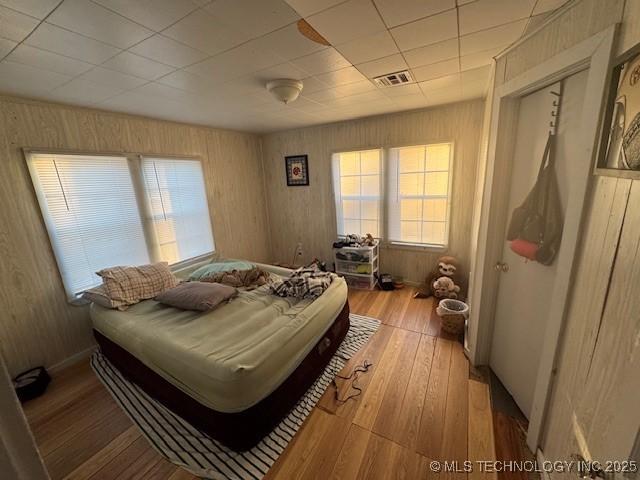 bedroom with a paneled ceiling and light hardwood / wood-style floors