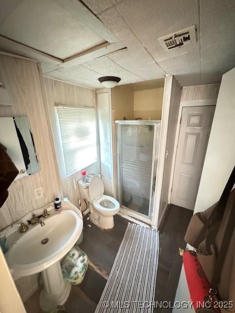 bathroom with toilet, a shower with shower door, and sink