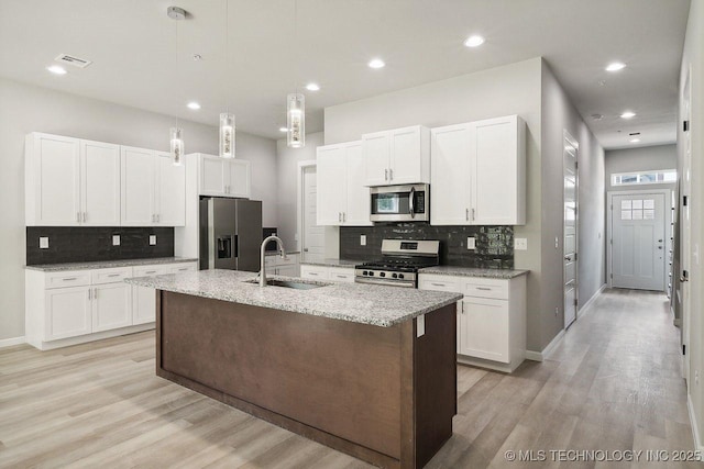 kitchen featuring sink, stainless steel appliances, an island with sink, and white cabinets