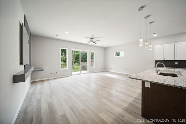 unfurnished living room featuring sink, ceiling fan, and light hardwood / wood-style flooring