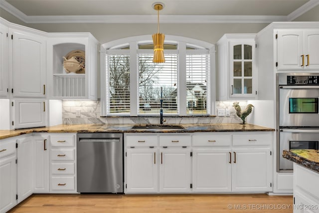 kitchen with sink, crown molding, dark stone countertops, stainless steel appliances, and white cabinets