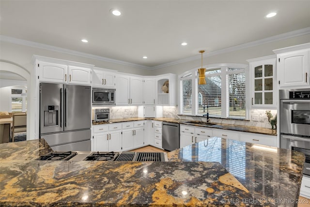 kitchen with stainless steel appliances, ornamental molding, backsplash, and a sink