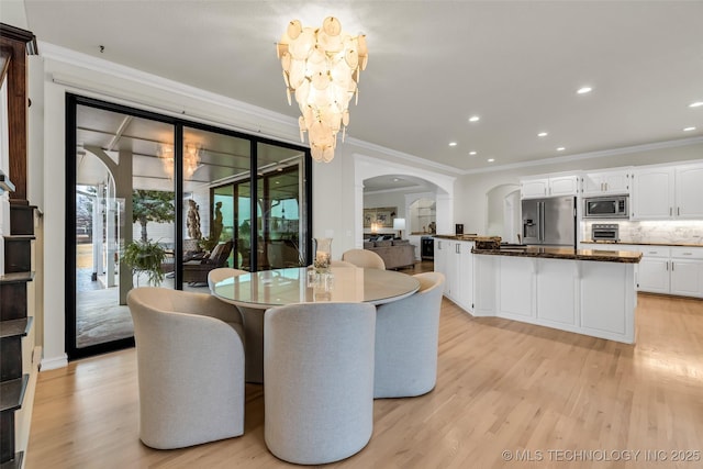 dining space with ornamental molding, a chandelier, and light hardwood / wood-style floors