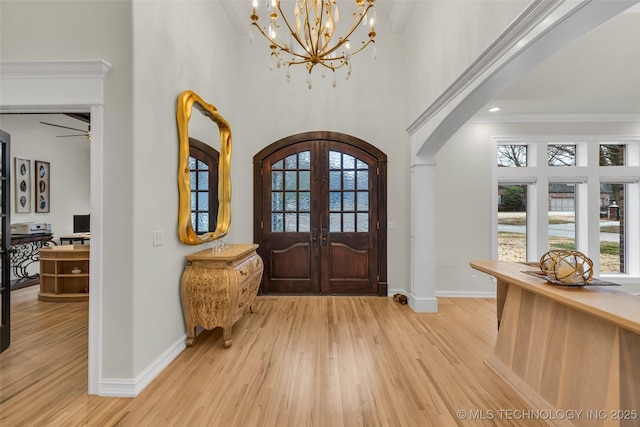 foyer with plenty of natural light, ornamental molding, french doors, and light wood-type flooring