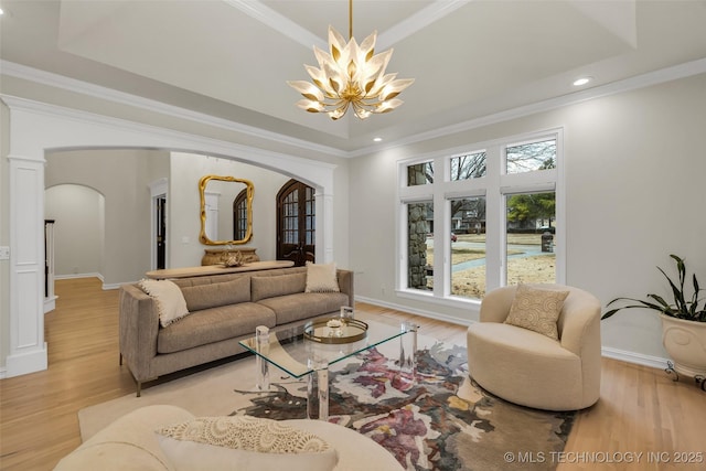 living room with a raised ceiling, crown molding, and light hardwood / wood-style floors