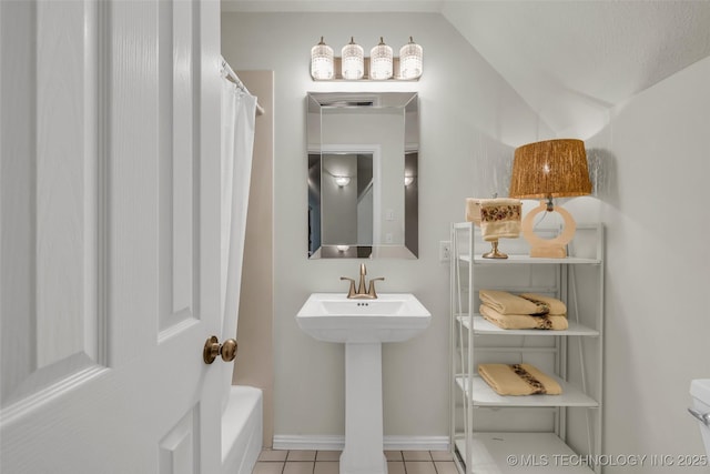 bathroom featuring curtained shower, sink, tile patterned flooring, and vaulted ceiling