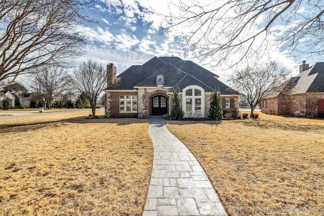 french country home with french doors and a chimney