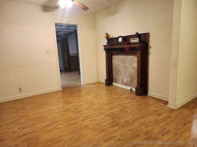 unfurnished living room featuring ceiling fan, baseboards, and wood finished floors