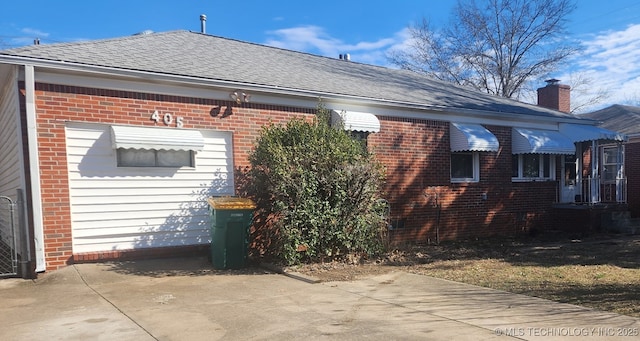 view of side of property with brick siding and roof with shingles