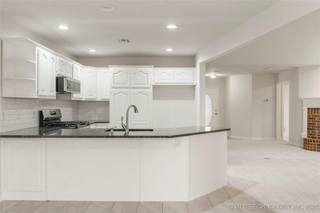 kitchen with sink, appliances with stainless steel finishes, white cabinetry, kitchen peninsula, and dark stone counters