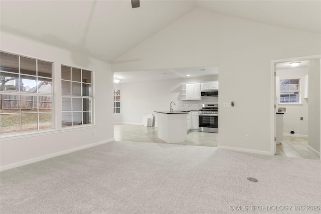 unfurnished living room featuring sink, a wealth of natural light, light colored carpet, and high vaulted ceiling