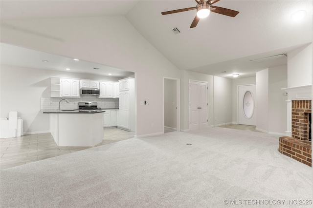 unfurnished living room with sink, a fireplace, high vaulted ceiling, and light carpet