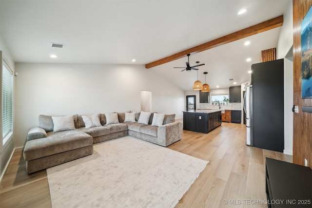 living room with vaulted ceiling with beams, light hardwood / wood-style floors, and ceiling fan